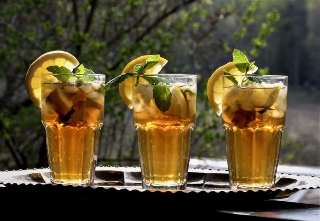 Bild på tre glas med iste, serverade med en skiva citron och en kvist pepparmynta. 