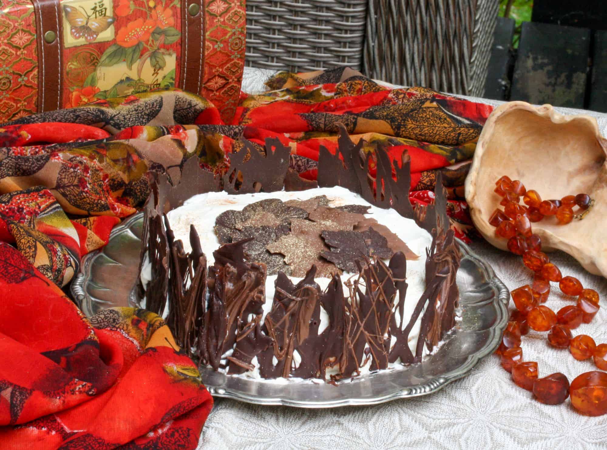 Bild på en svensk Schwarzwaldtårta med vacker chokladdekoration i form av trädstammar och löv. 