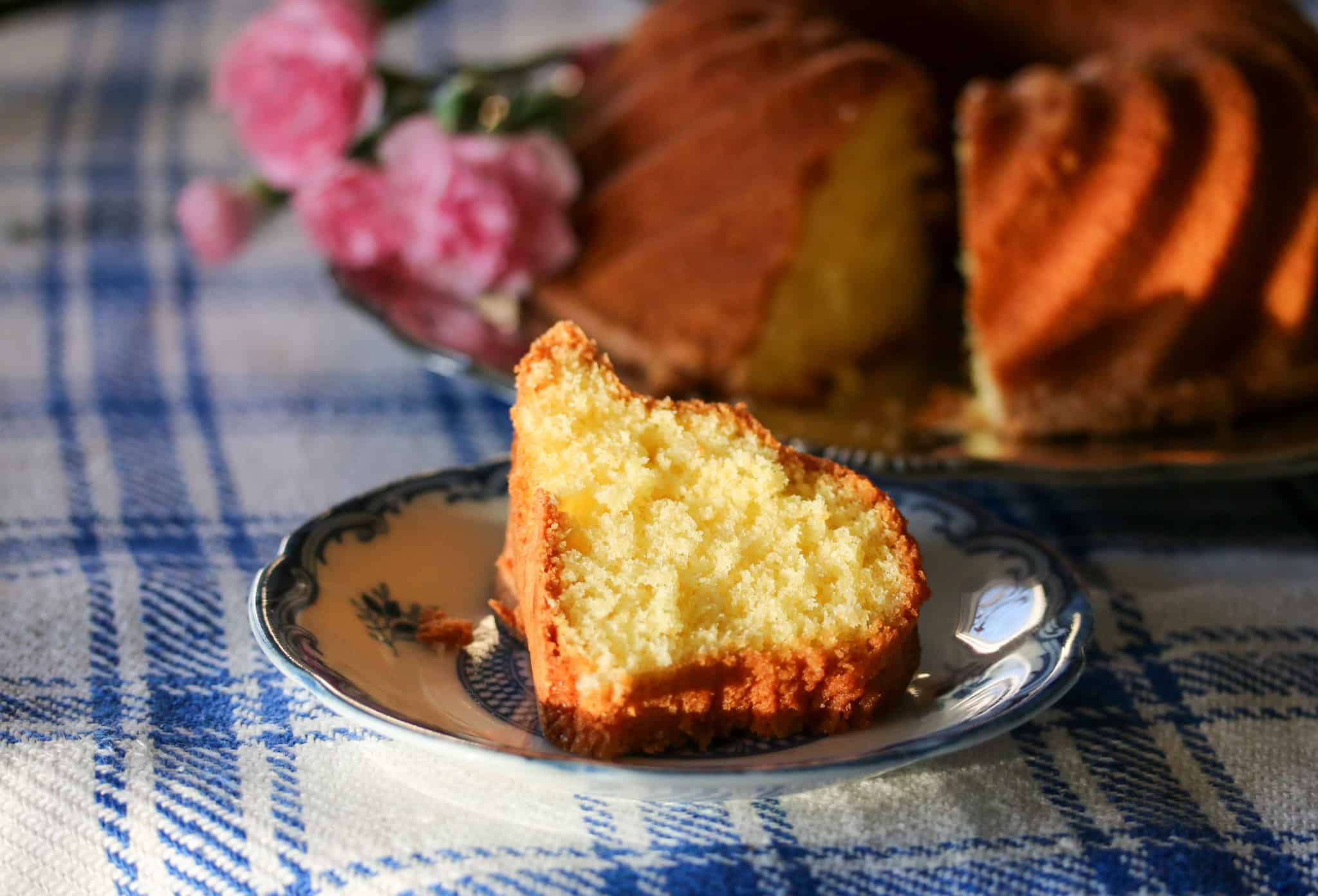 Skiva favoritkaka - sockerkaka - på ett litet fat med i bakgrunden hela kakan.